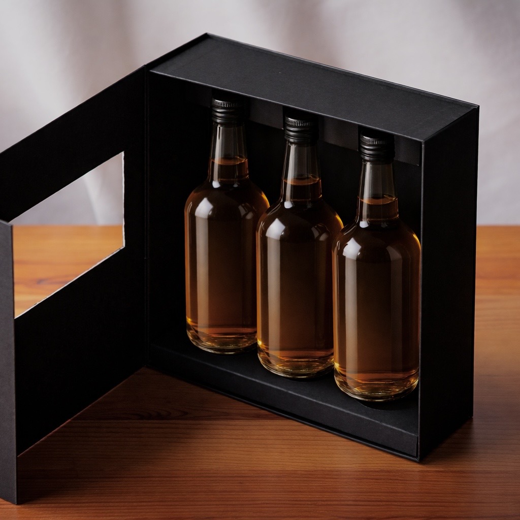 開閉式の黒貼り箱にアンバーボトル3本を収めた高級ウイスキーギフトパッケージ